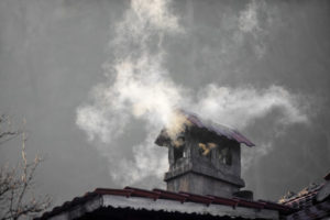 Chimney with metal roof has smoke coming out of it