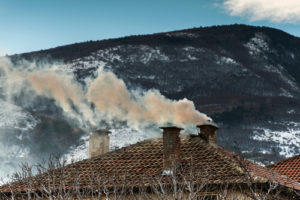 Three Chimneys with smoke coming out in from on mountain and blue sky