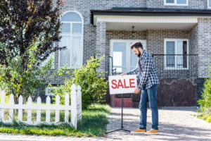 Man putting sale sign out in front of home