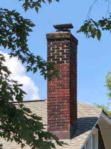 Brick Chimney with tree branches around it and blue sky