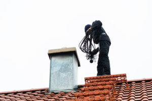 Chimney Sweep on Roof next to chimney doing inspection