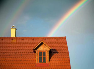 Brown Roof and Chimney with two Rainbows in the sky behind it