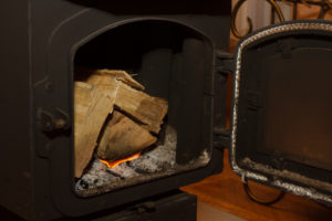 Wood stove open showing three pieces of firewood